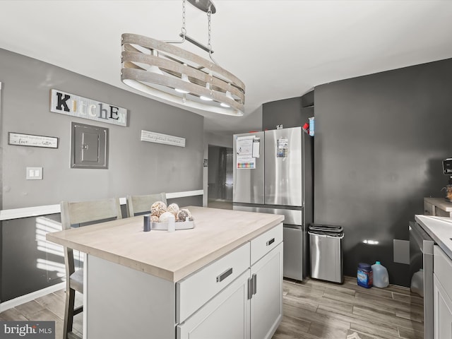 kitchen featuring a breakfast bar area, stainless steel fridge, a kitchen island, and white cabinets