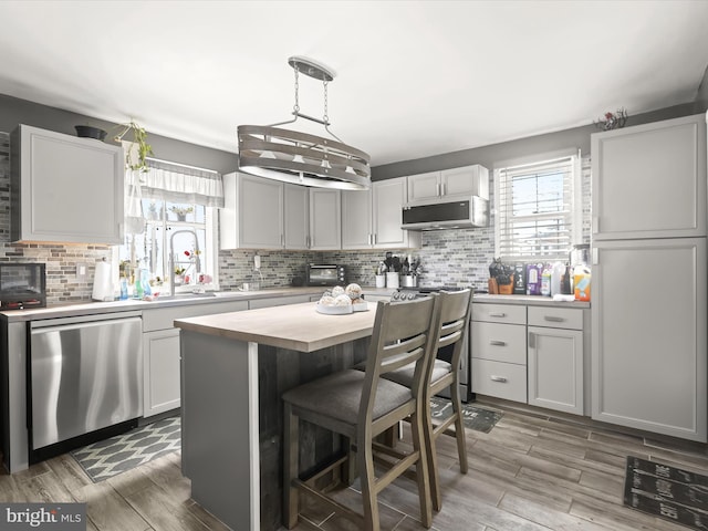 kitchen with pendant lighting, dishwasher, backsplash, a center island, and white cabinets