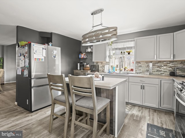 kitchen featuring hanging light fixtures, stainless steel appliances, a center island, light hardwood / wood-style floors, and white cabinets