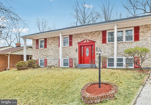 split foyer home featuring entry steps, a front lawn, and brick siding