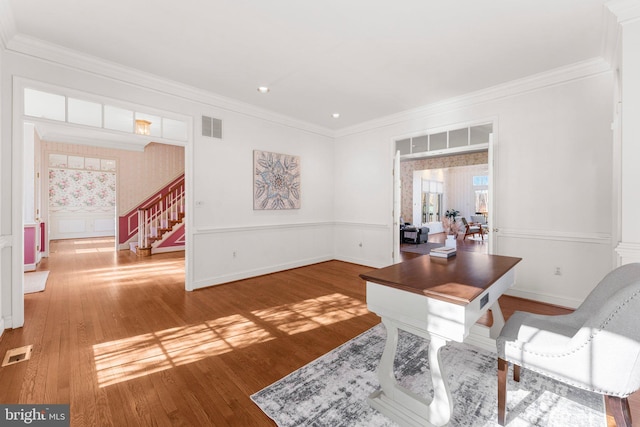 office with a wainscoted wall, visible vents, wood finished floors, and ornamental molding