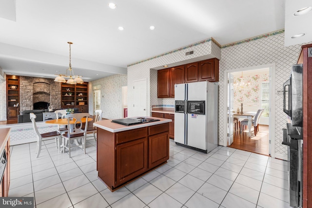 kitchen with wallpapered walls, a center island, hanging light fixtures, light countertops, and white fridge with ice dispenser