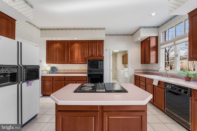 kitchen featuring light countertops, a kitchen island, a sink, and black appliances