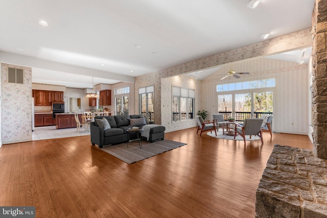 living area with wallpapered walls, visible vents, baseboards, a ceiling fan, and light wood-type flooring