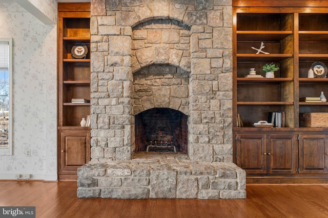 unfurnished living room featuring baseboards, a fireplace, wood finished floors, and wallpapered walls