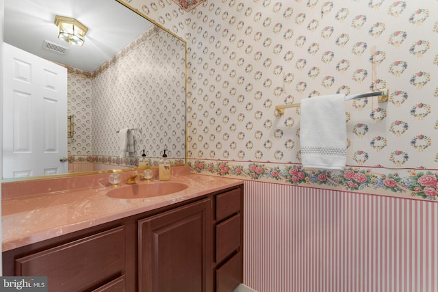 bathroom featuring visible vents, vanity, and wallpapered walls