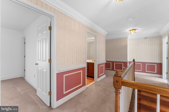 corridor featuring a wainscoted wall, crown molding, light carpet, an upstairs landing, and wallpapered walls