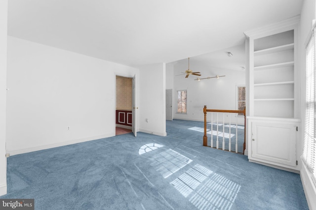 interior space with a ceiling fan, lofted ceiling, carpet flooring, and baseboards