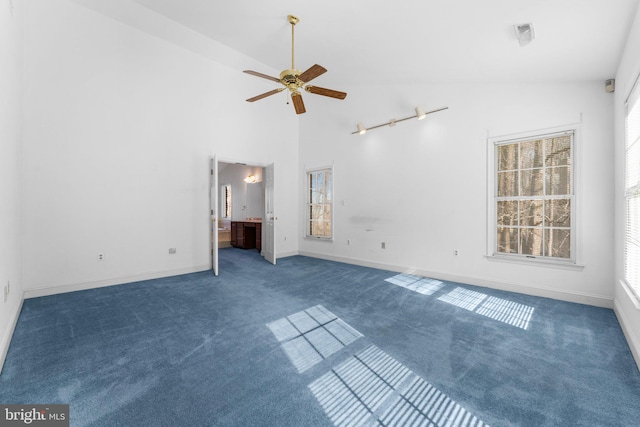 interior space featuring ceiling fan, high vaulted ceiling, dark carpet, and baseboards