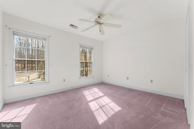 empty room featuring light carpet, a ceiling fan, visible vents, and baseboards