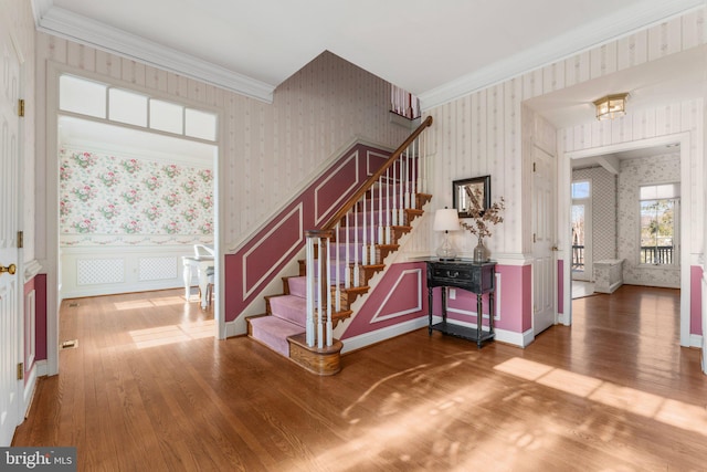 foyer entrance featuring crown molding, wainscoting, and wallpapered walls