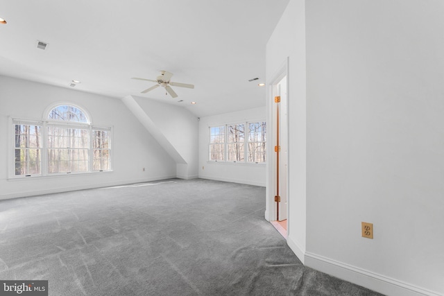 unfurnished living room featuring carpet floors, visible vents, a ceiling fan, vaulted ceiling, and baseboards