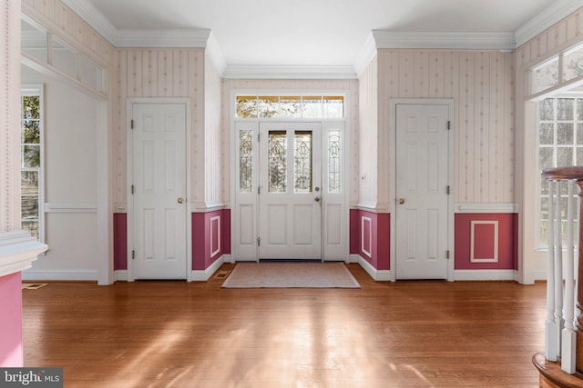 entryway with ornamental molding, wood finished floors, and wallpapered walls