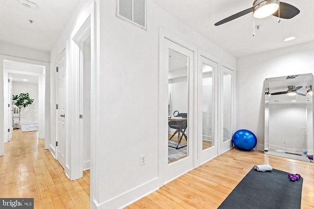 exercise room with ceiling fan and wood-type flooring