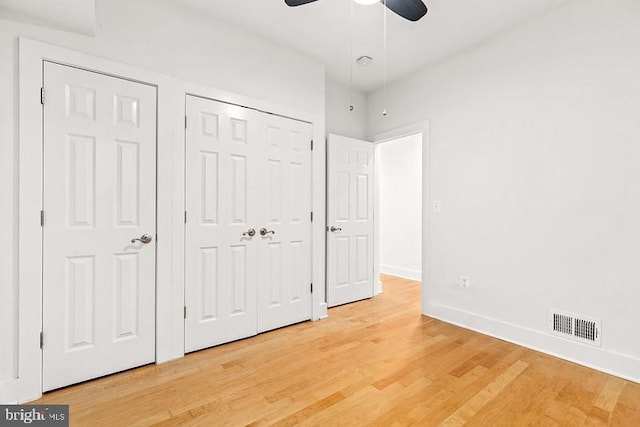 unfurnished bedroom with hardwood / wood-style floors, two closets, and ceiling fan