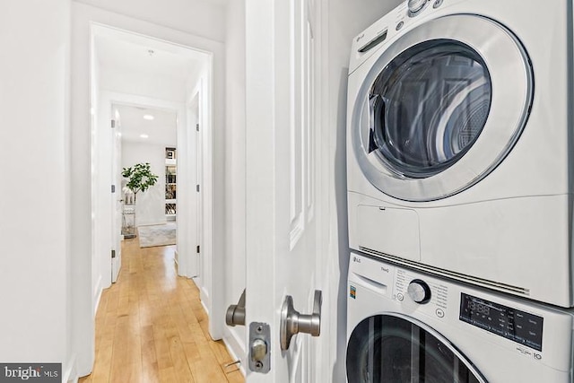 laundry room with stacked washer and clothes dryer and light wood-type flooring