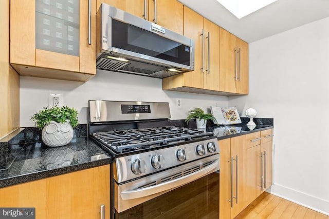 kitchen featuring stainless steel appliances, dark stone countertops, and light hardwood / wood-style flooring