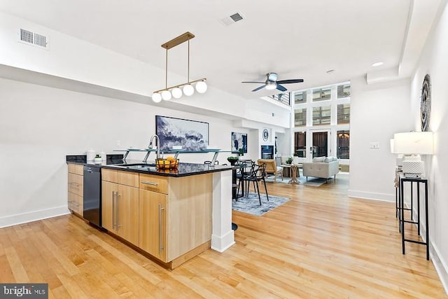 kitchen featuring a breakfast bar area, dishwasher, ceiling fan, hanging light fixtures, and light hardwood / wood-style floors