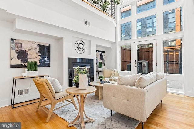 living room with a towering ceiling and light hardwood / wood-style flooring