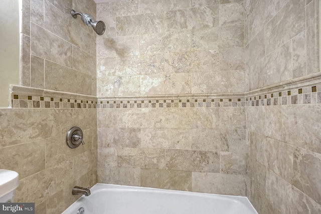 bathroom with tiled shower / bath and toilet