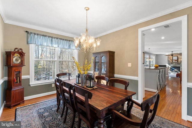 dining area with ornamental molding, hardwood / wood-style floors, and a chandelier