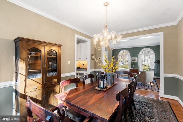 dining area with wood-type flooring, a notable chandelier, and crown molding