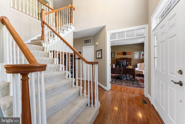 entryway featuring hardwood / wood-style flooring and a towering ceiling