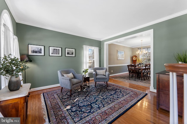 living area featuring an inviting chandelier, crown molding, and wood-type flooring