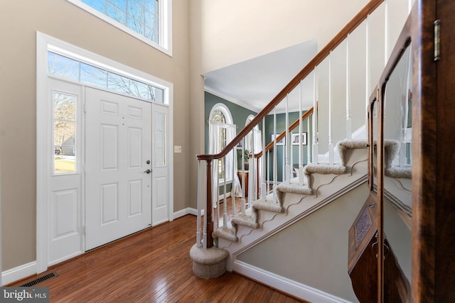 foyer featuring hardwood / wood-style floors, ornamental molding, and a high ceiling