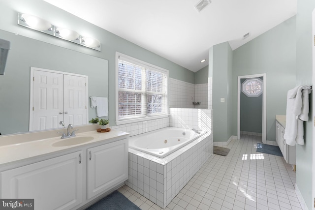 bathroom with vanity, lofted ceiling, a relaxing tiled tub, and tile patterned floors