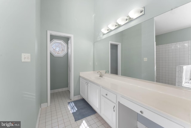 bathroom with tile patterned flooring, vanity, and a tile shower