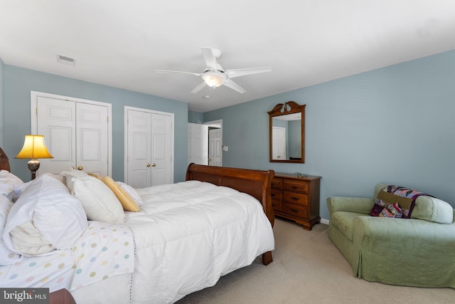 carpeted bedroom featuring ceiling fan and two closets