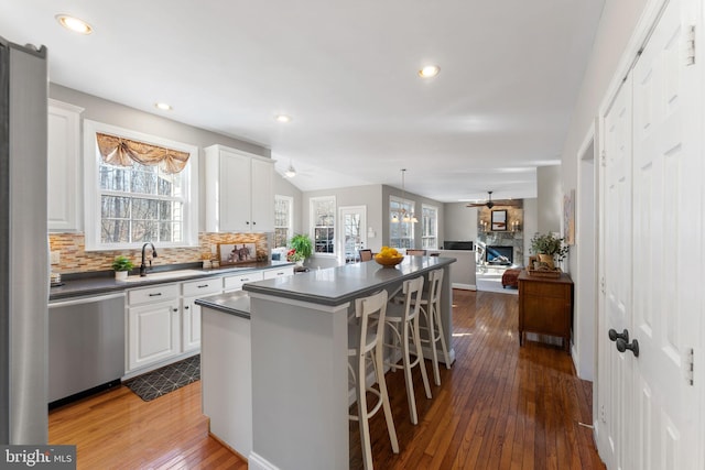 kitchen with a kitchen bar, sink, dishwasher, a kitchen island, and white cabinets