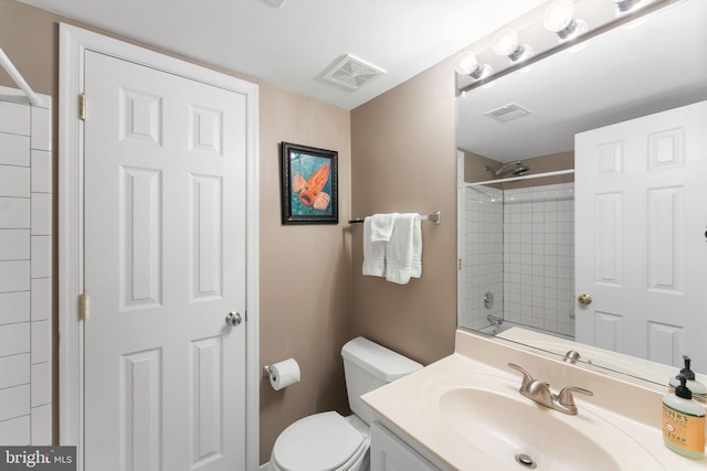 bathroom with tiled shower, vanity, and toilet