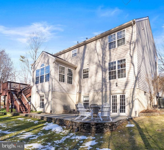 rear view of property featuring french doors, a patio area, and a lawn