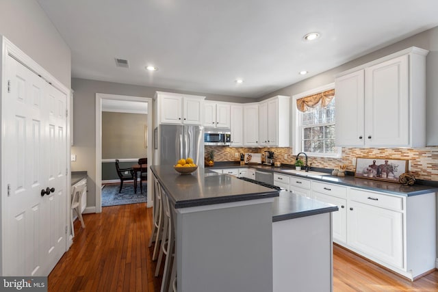 kitchen featuring a kitchen island, sink, white cabinets, a kitchen breakfast bar, and stainless steel appliances