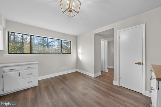 unfurnished bedroom with multiple windows, dark wood-type flooring, and a chandelier