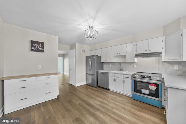 kitchen with pendant lighting, sink, appliances with stainless steel finishes, tasteful backsplash, and white cabinets