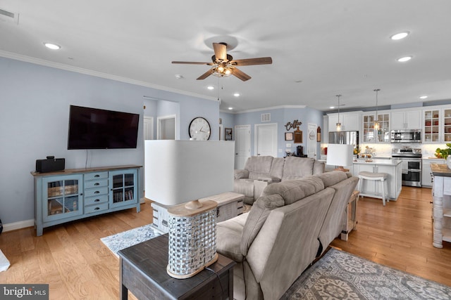 living room with crown molding, ceiling fan, and light wood-type flooring