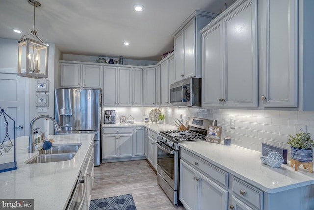 kitchen with pendant lighting, tasteful backsplash, sink, stainless steel appliances, and light stone countertops