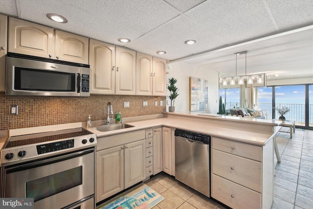 kitchen featuring appliances with stainless steel finishes, decorative light fixtures, sink, backsplash, and kitchen peninsula