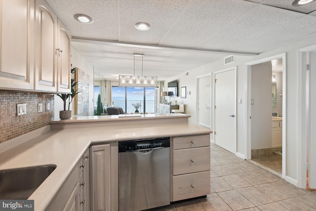 kitchen featuring pendant lighting, dishwasher, backsplash, light tile patterned floors, and a drop ceiling