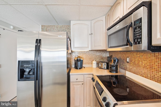 kitchen with white cabinetry, a paneled ceiling, appliances with stainless steel finishes, and backsplash