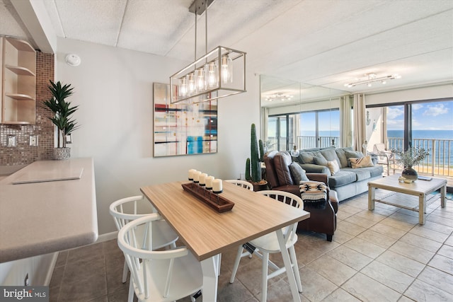 dining area featuring a water view, light tile patterned floors, and a textured ceiling