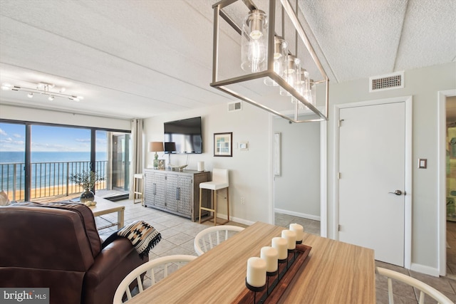 living room featuring a water view, a textured ceiling, and light tile patterned floors