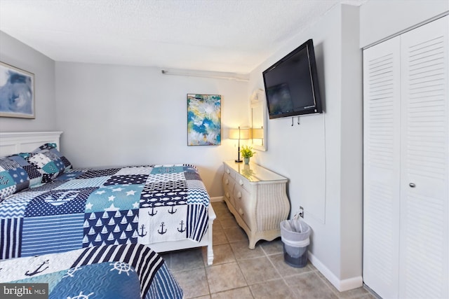 bedroom featuring light tile patterned floors, a closet, and a textured ceiling