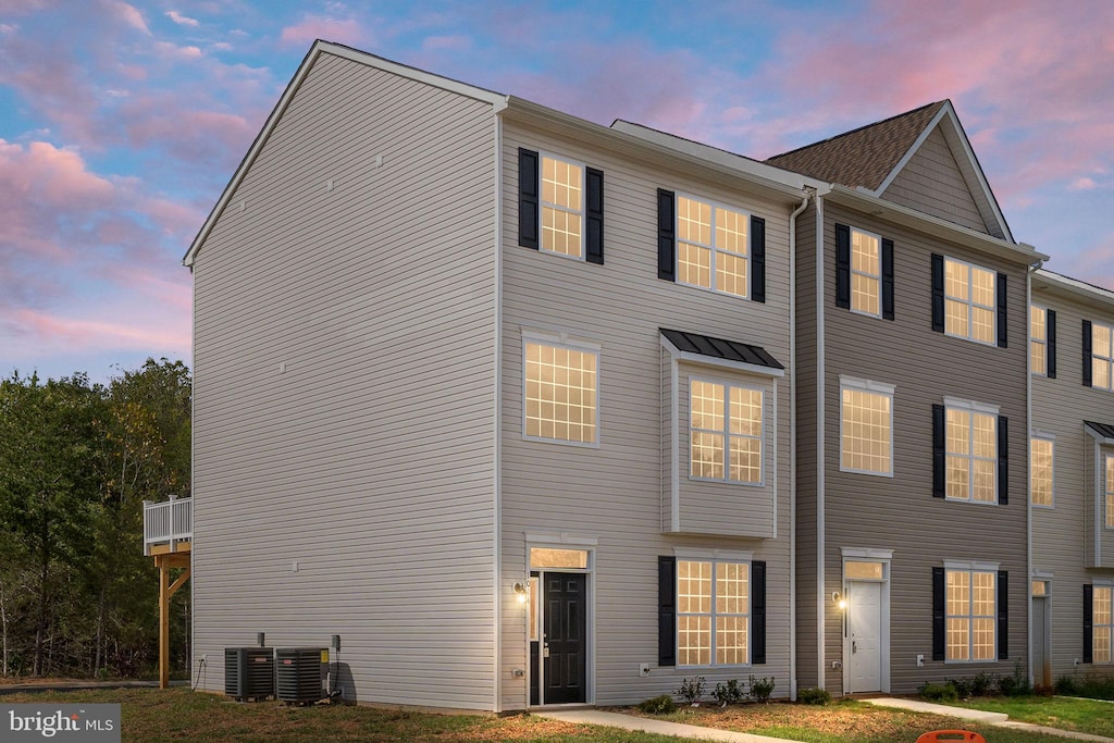 exterior space featuring central AC unit and a lawn