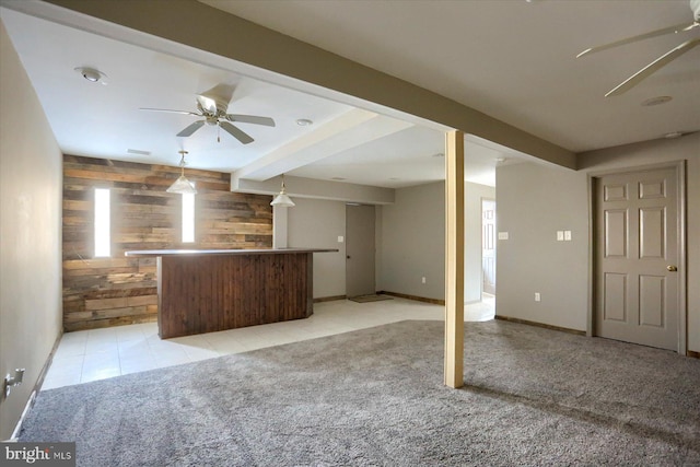 unfurnished living room with ceiling fan, indoor bar, light carpet, and wooden walls