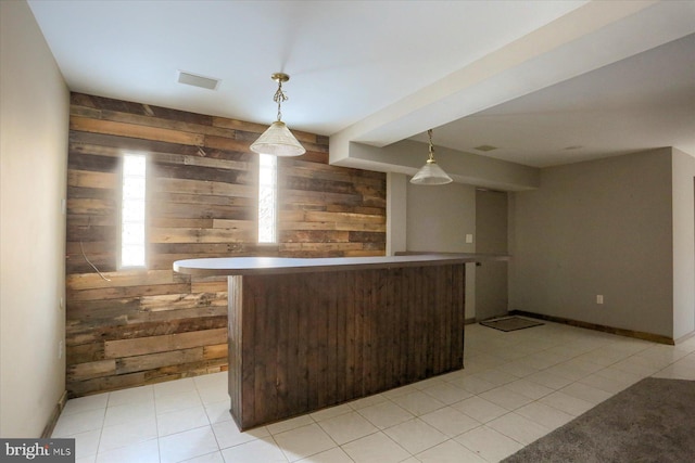 kitchen featuring hanging light fixtures, dark brown cabinets, and wood walls