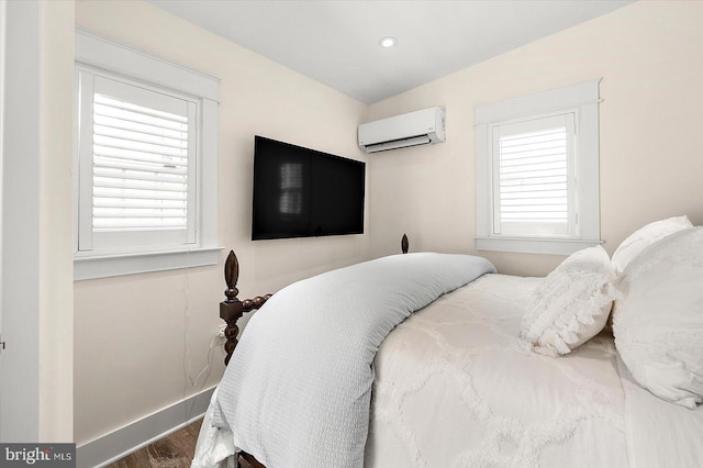 bedroom featuring hardwood / wood-style flooring, multiple windows, and a wall unit AC